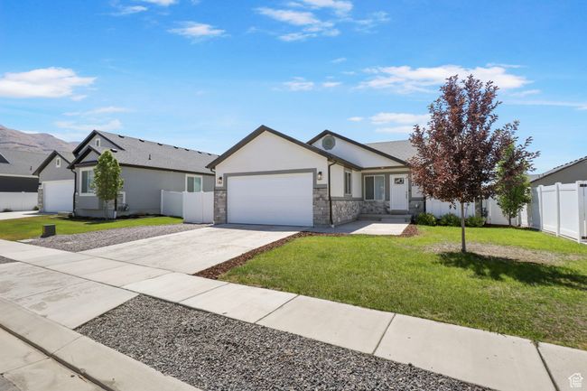 Single story home with stucco siding, a garage, driveway, and stone siding | Image 27