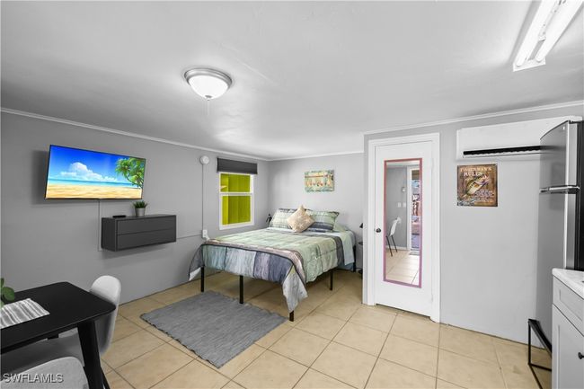 Bedroom with stainless steel refrigerator, a wall mounted AC, light tile patterned flooring, and crown molding | Image 32