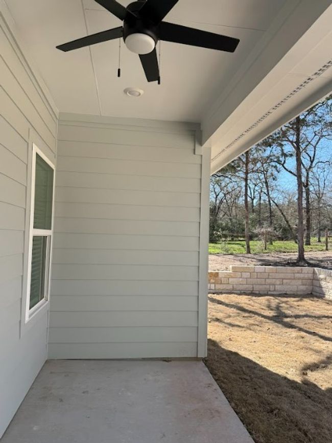 A serene covered back patio with ceiling fans, overlooking a lush yard—perfect for year-round relaxation. | Image 38