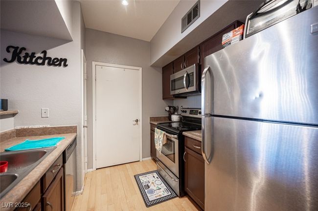 Kitchen with dark brown cabinets, light wood-style floors, visible vents, stainless steel appliances, and a sink | Image 14