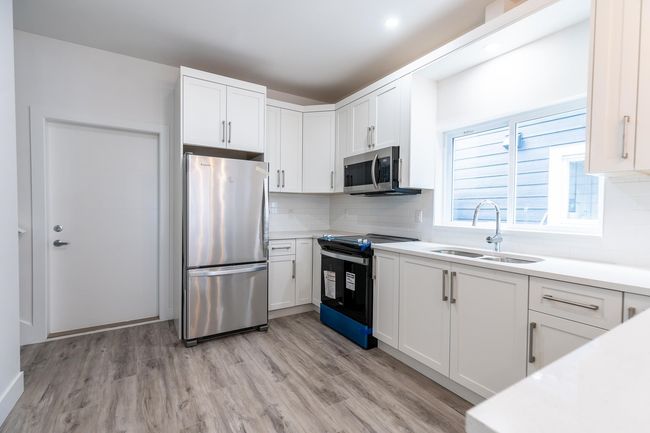 Kitchen with stainless steel appliances, a sink, and white cabinetry | Image 9