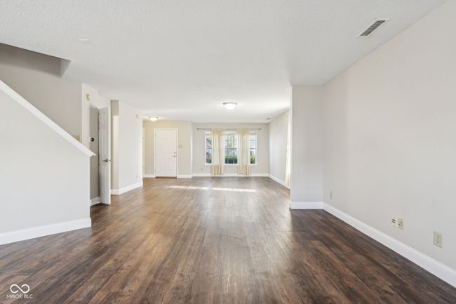 unfurnished living room featuring dark wood-style floors, baseboards, and stairway | Image 17