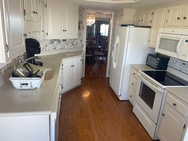 Kitchen featuring a sink, dark wood finished floors, white appliances, white cabinets, and light countertops | Image 12
