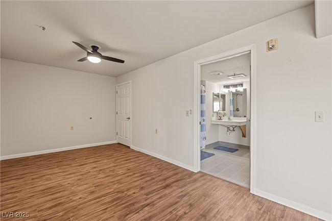 Unfurnished bedroom with ceiling fan, wood finished floors, connected bathroom, and baseboards | Image 13