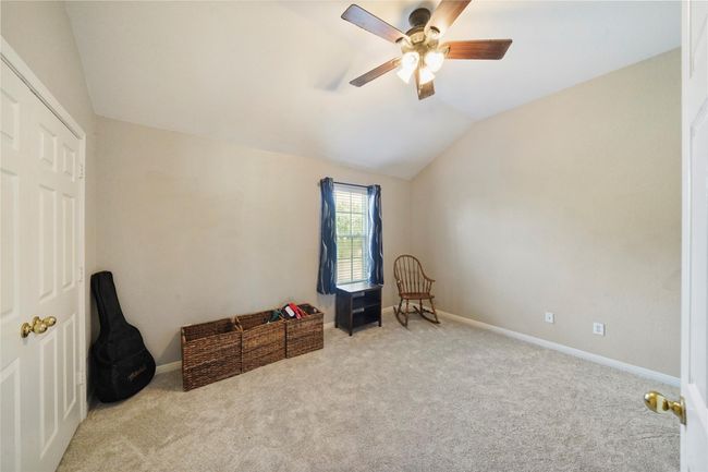 This bedroom or workout room right off the gameroom features neutral walls and carpet, a ceiling fan, and a window with natural light. It's equipped with a closet and offers a simple, versatile space suitable for various uses. | Image 24