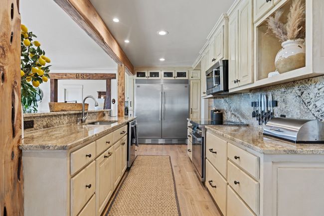 Kitchen with stainless steel appliances, light wood-type flooring, recessed lighting, glass insert cabinets, and light stone counters | Image 22