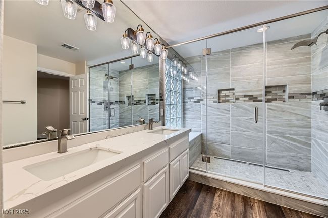 Full bathroom with double vanity, a stall shower, and wood finished floors | Image 33