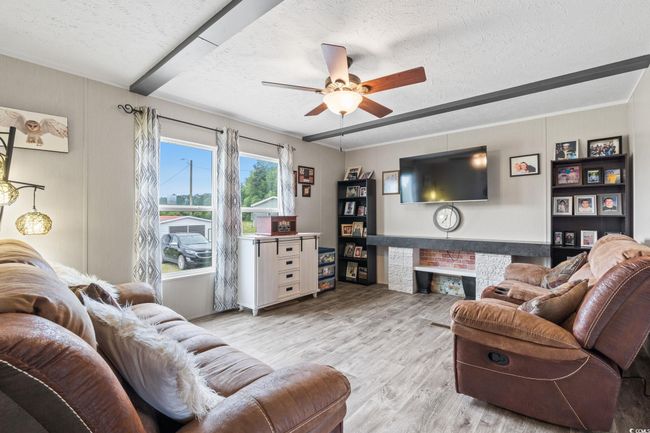 Living area featuring a textured ceiling, wood finished floors, and ceiling fan | Image 22