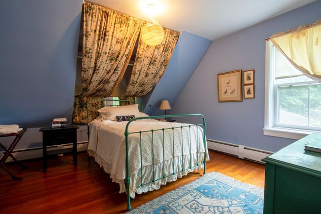 Bedroom with a baseboard heating unit, a baseboard radiator, vaulted ceiling, and wood finished floors | Image 10