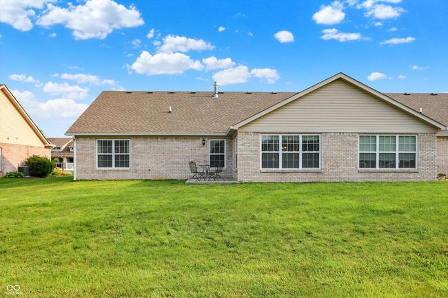 Rear view of property featuring brick siding, roof with shingles, and a yard | Image 36