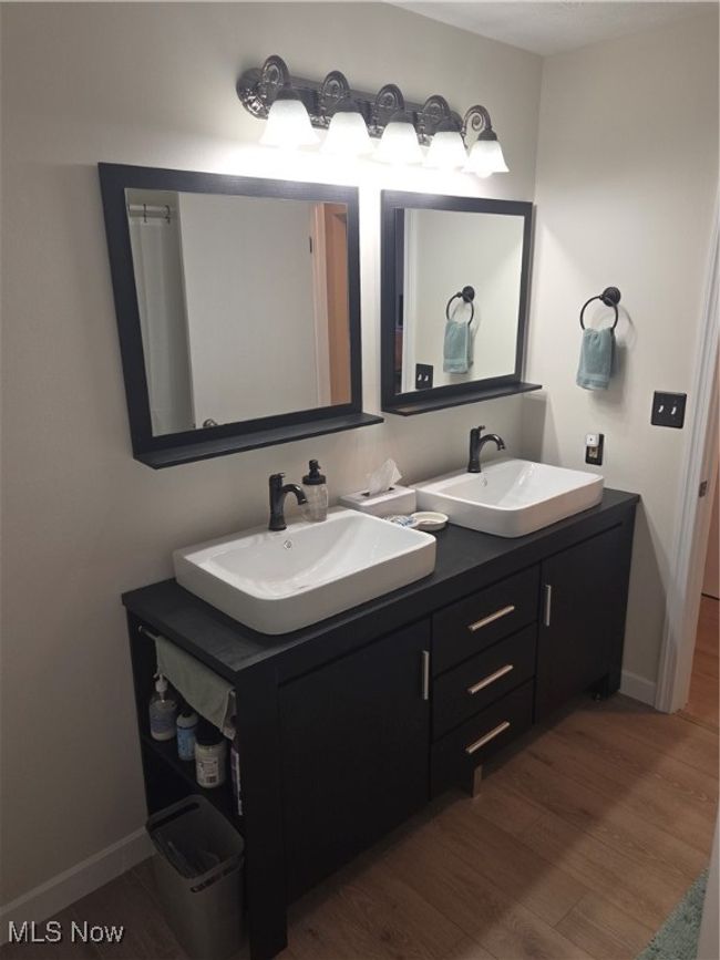 Bathroom with double vanity, a sink, and wood finished floors | Image 24
