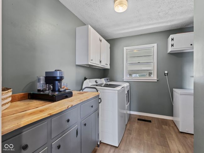 clothes washing area featuring baseboards, a textured ceiling, washing machine and clothes dryer, laundry area, and wood finished floors | Image 14