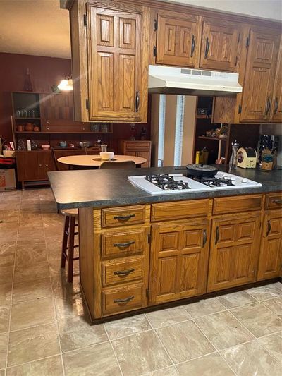 Kitchen featuring a breakfast bar, kitchen peninsula, range hood, and cooktop | Image 3