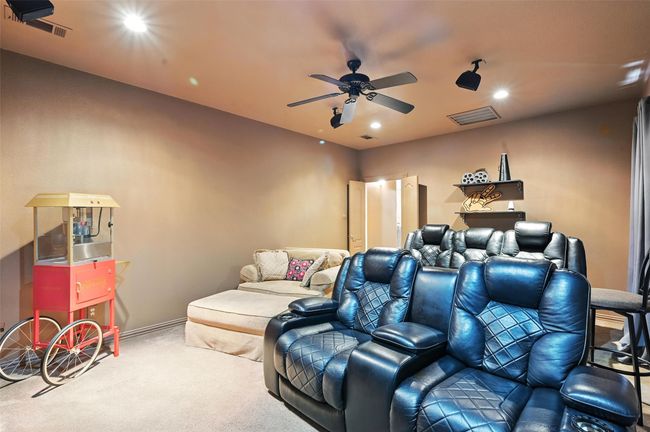 Carpeted home theater room with a ceiling fan and recessed lighting | Image 23
