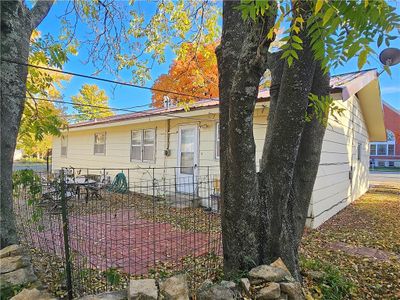 View of back of property with a brick patio and fenced yard. | Image 3