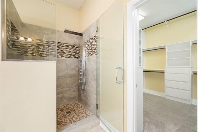 The primary bath offers a luxurious, spa-like experience with dual sinks, a jetted soaking tub, and a seamless glass shower. Designed for both comfort and functionality, it features ample counter space and storage, creating a clean and elegant atmosphere. | Image 17