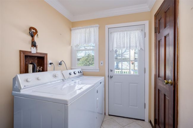 Laundry room with light tile patterned floors, independent washer and dryer, ornamental molding, and laundry area | Image 20