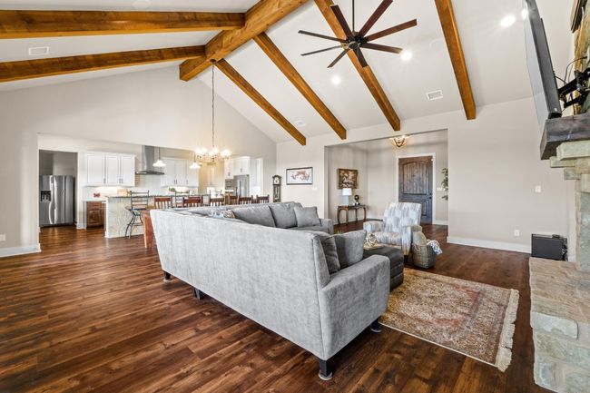 Living area featuring high vaulted ceiling, ceiling fan with notable chandelier, dark wood finished floors, baseboards, and beam ceiling | Image 8
