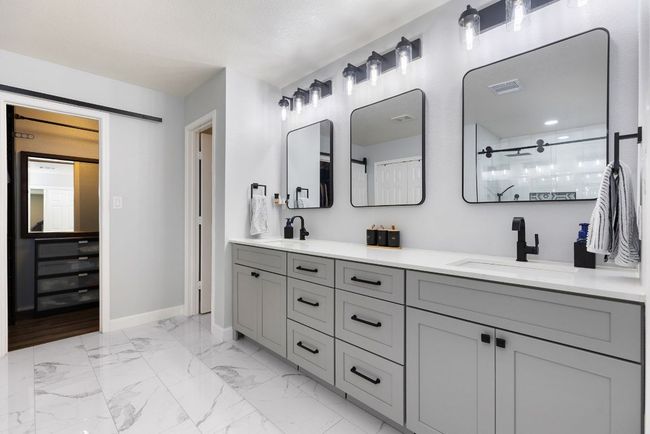 Bathroom featuring double vanity, baseboards, tiled shower, and marble finish flooring | Image 24