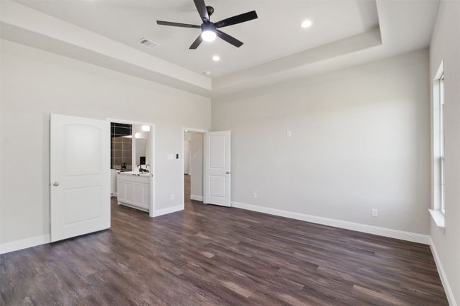 Unfurnished bedroom with visible vents, baseboards, dark wood finished floors, a tray ceiling, and recessed lighting | Image 9