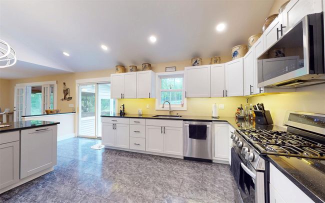 Kitchen featuring stainless steel appliances, a sink, white cabinetry, recessed lighting, and lofted ceiling | Image 20