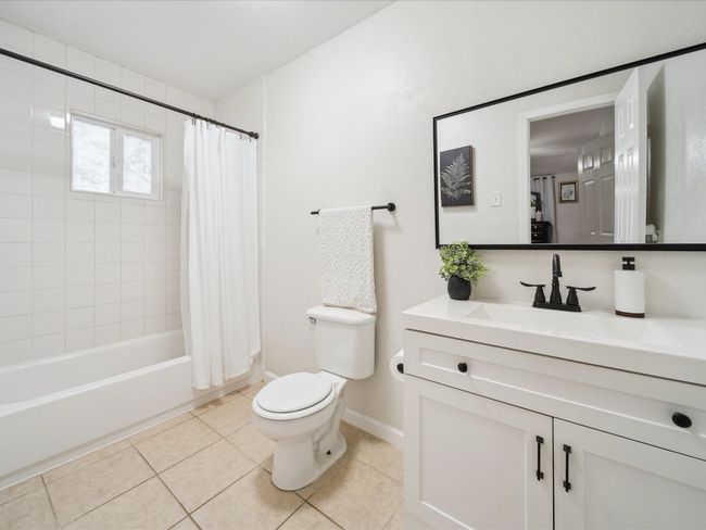 Full bath featuring toilet, tile patterned flooring, vanity, shower / bath combo with shower curtain, and baseboards | Image 10