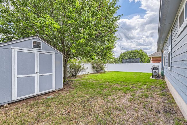 View of yard featuring a fenced backyard, an outdoor structure, and a shed | Image 27