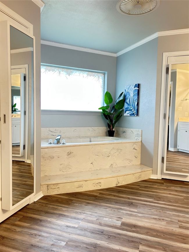 Full bathroom featuring baseboards, a garden tub, wood finished floors, and crown molding | Image 29