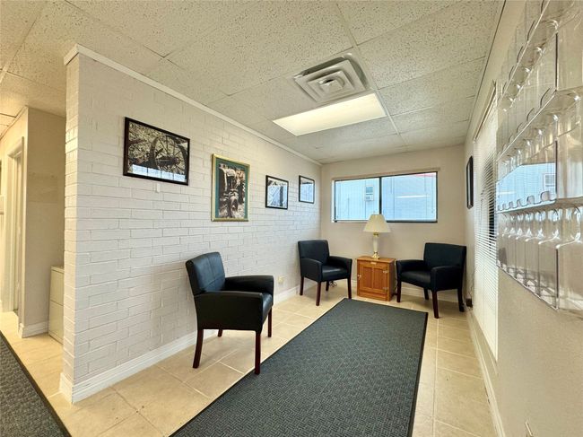 Sitting room featuring a paneled ceiling, brick wall, and tile patterned flooring | Image 30