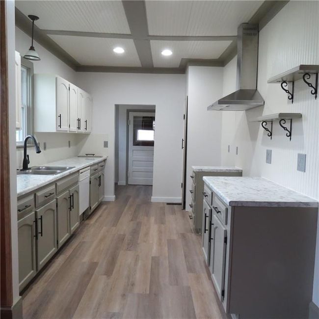 Kitchen with open shelves, stainless steel range hood, dishwasher, a sink, and new floors and countertops | Image 26