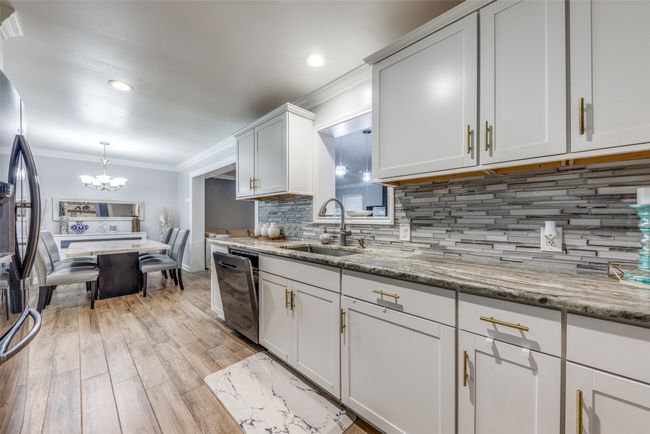 Kitchen featuring freestanding refrigerator, stainless steel dishwasher, a chandelier, ornamental molding, and tasteful backsplash | Image 12