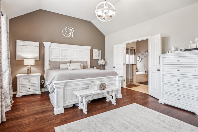 Bedroom featuring a chandelier, vaulted ceiling, wood finished floors, and ensuite bathroom | Image 14