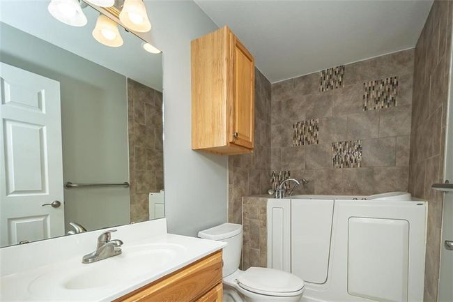 Full bathroom with a garden tub, tile walls, vanity, and toilet | Image 28