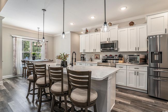 Kitchen with appliances with stainless steel finishes, crown molding, dark wood-style floors, recessed lighting, and white cabinets | Image 9