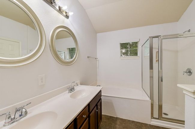 Full bathroom featuring a stall shower, a garden tub, double vanity, tile patterned flooring, and vaulted ceiling | Image 15