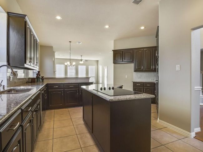 Kitchen featuring black electric stovetop, tasteful backsplash, a chandelier, light tile patterned flooring, and recessed lighting | Image 6
