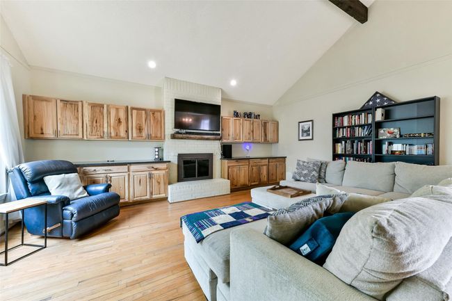 This spacious living room features high ceilings, a cozy fireplace & built-in wooden cabinets. Natural light streams through large windows, enhancing the inviting atmosphere. | Image 10