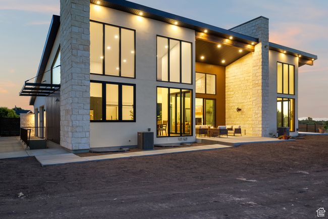 Back of property at dusk featuring an outdoor hangout area, a chimney, a balcony, and stone siding | Image 82