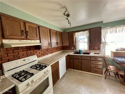 Kitchen with white appliances, rail lighting, backsplash, and sink | Image 2