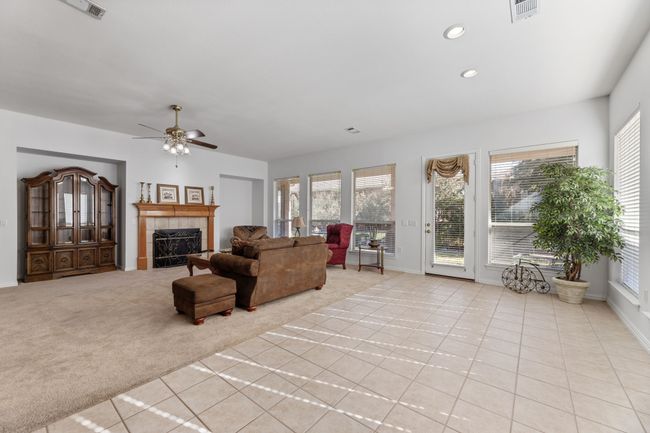 Carpeted living room featuring ceiling fan, plenty of natural light, and a fireplace | Image 14