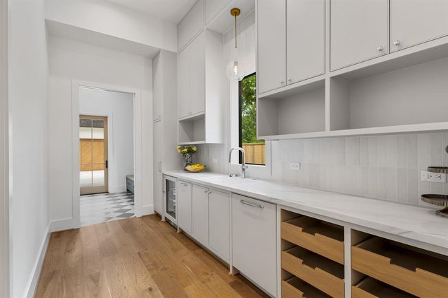 Butler's pantry and staging area hidden behind the kitchen is equipped with wine fridge, sink, dishwasher and ample storage. | Image 11