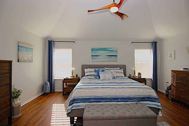 Bedroom with a ceiling fan, multiple windows, wood look Luxury Vinal Plank floors, and baseboards | Image 31