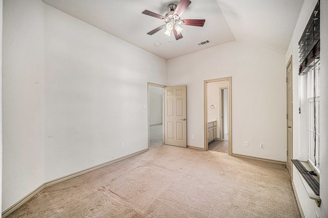 Unfurnished bedroom featuring light colored carpet, lofted ceiling, ensuite bath, baseboards, and ceiling fan | Image 22