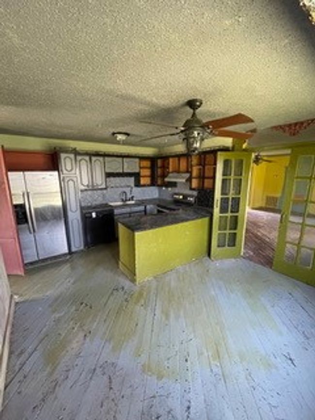 Kitchen featuring ceiling fan, a textured ceiling, dark countertops, stainless steel fridge, and hardwood / wood-style floors | Image 24