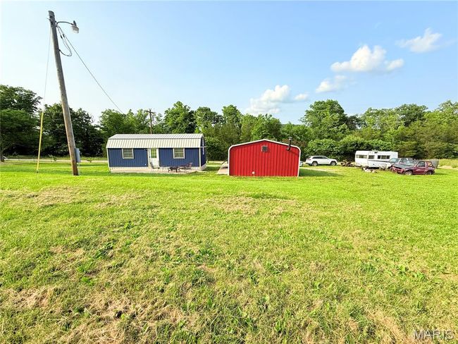 View of green lawn featuring an outdoor structure and view of wooded area | Image 44