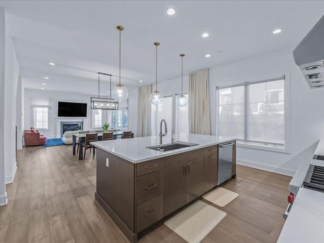 Kitchen with light countertops, stainless steel dishwasher, a sink, dark brown cabinets, and wood finished floors | Image 9
