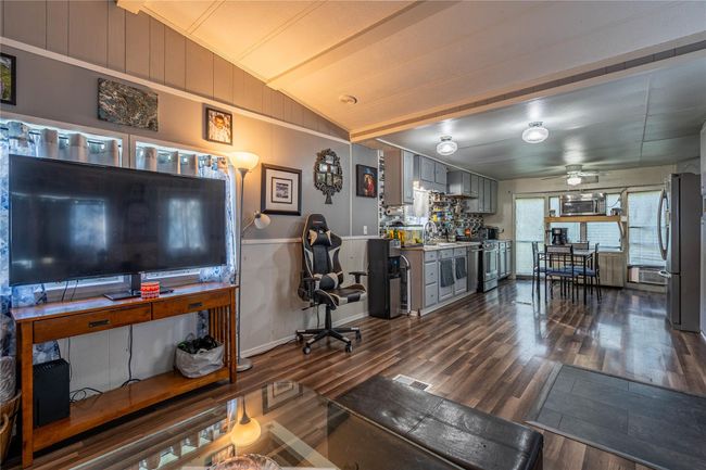 Living area with dark wood finished floors, ceiling fan, and lofted ceiling | Image 9