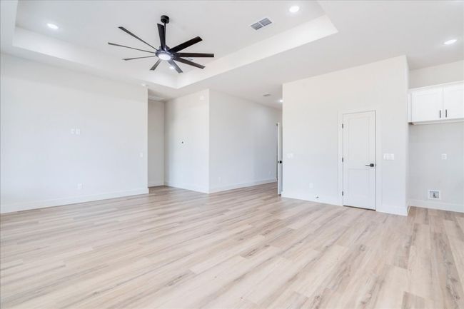 Unfurnished living room with a raised ceiling, a ceiling fan, light wood-type flooring, and recessed lighting | Image 7