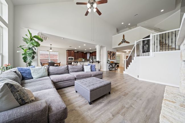 Living room with a ceiling fan, high vaulted ceiling, stairs, light wood-style floors, and recessed lighting | Image 5