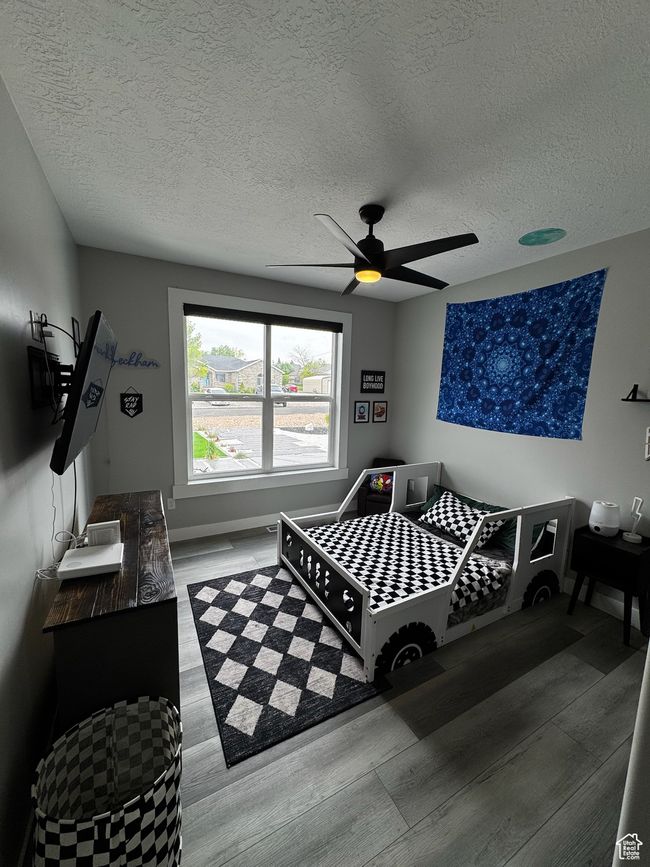 Bedroom featuring wood finished floors, a textured ceiling, ceiling fan, and baseboards | Image 13